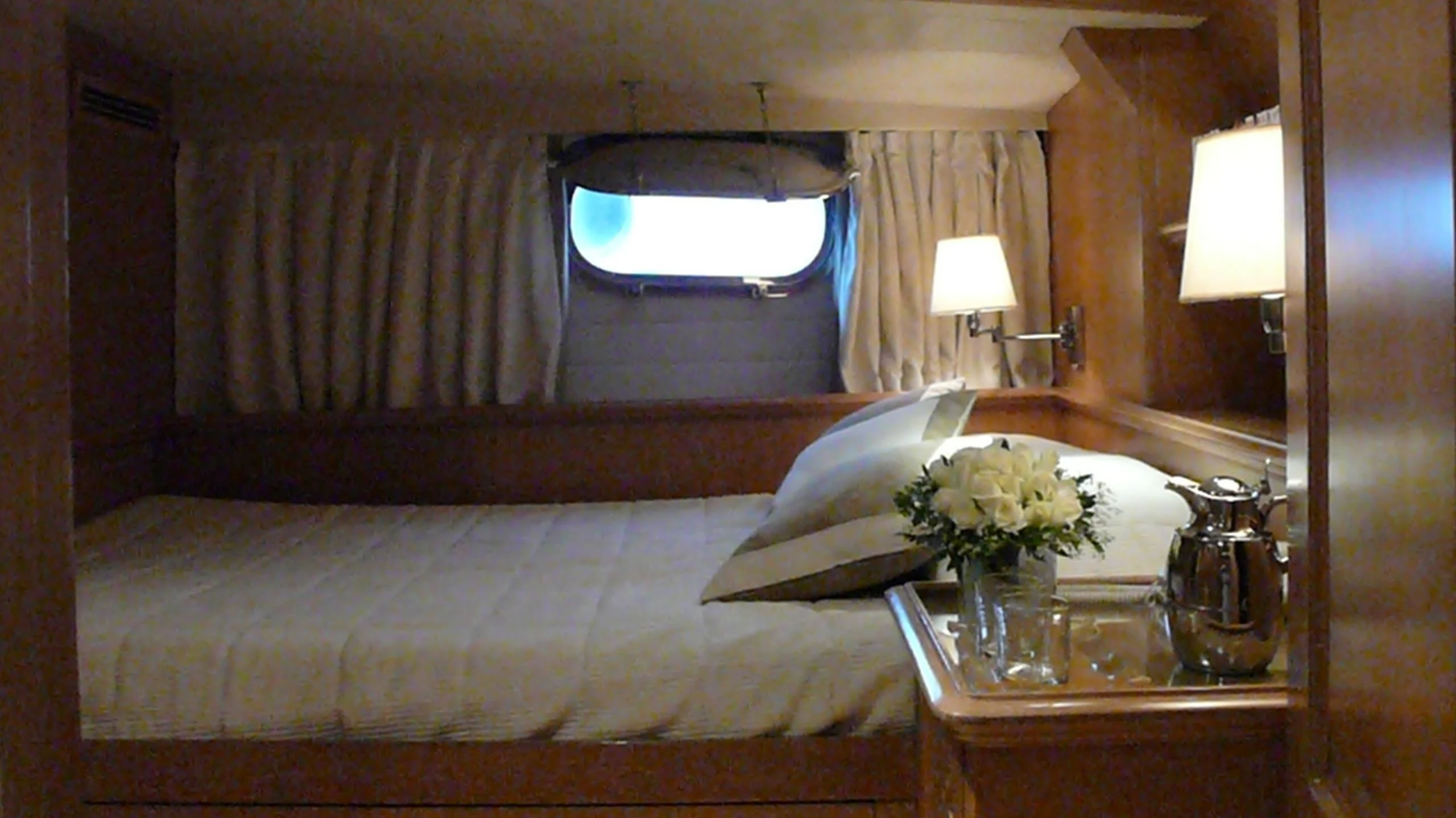 a bed with a table and a lamp in a room aboard ALTHEA Yacht for Sale