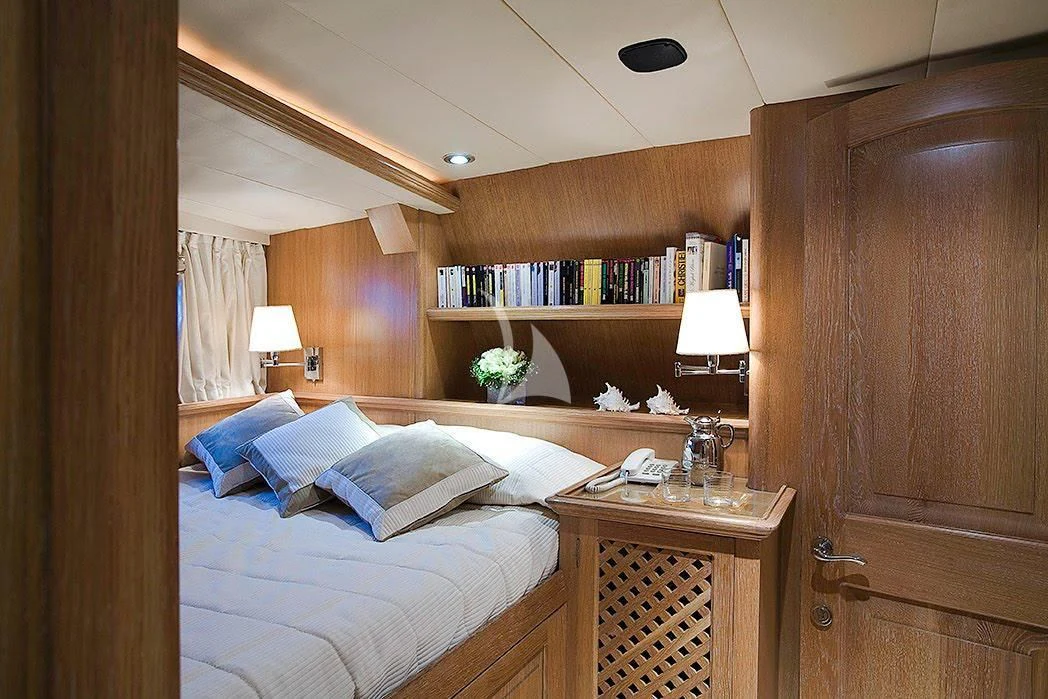 a bedroom with a bed and a bookcase aboard ALTHEA Yacht for Sale