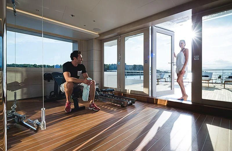 a man sitting in a chair in a room with a wood floor and a woman standing in the aboard VOLPINI 2 Yacht for Sale