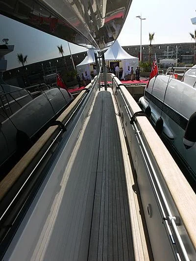 a long metal railing with a metal railing and a building with a white tent and people and trees aboard SOFIA Y Yacht for Sale