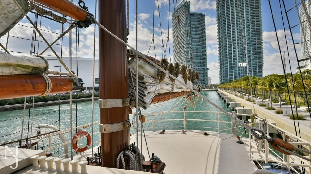 a large white boat with a large ship in the background aboard PEACEMAKER Yacht for Sale