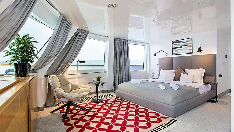a bedroom with a bed and a chair aboard AZALEA Yacht for Sale