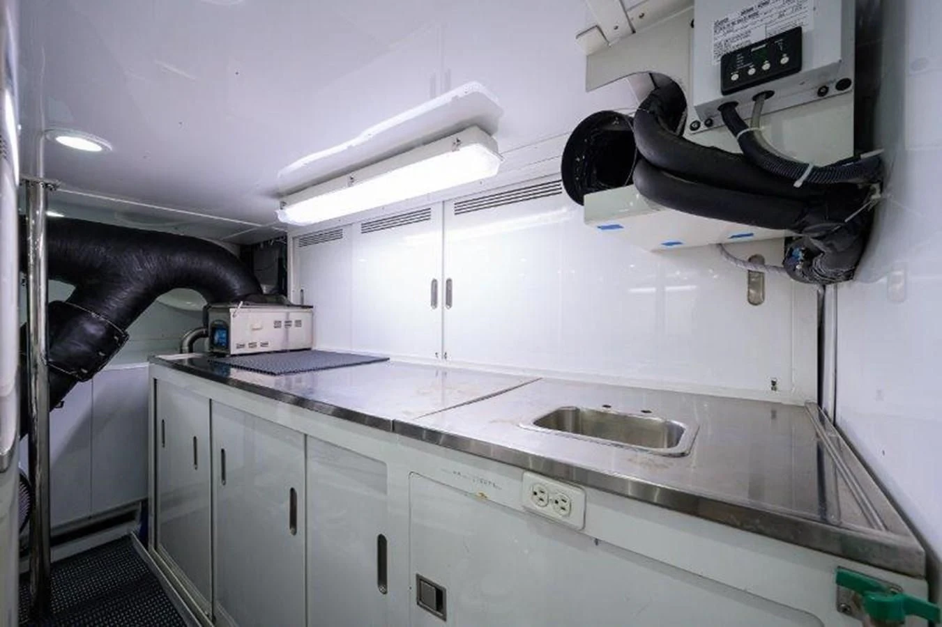 a white kitchen with a large white counter top and black faucet aboard ODYSSEY Yacht for Sale