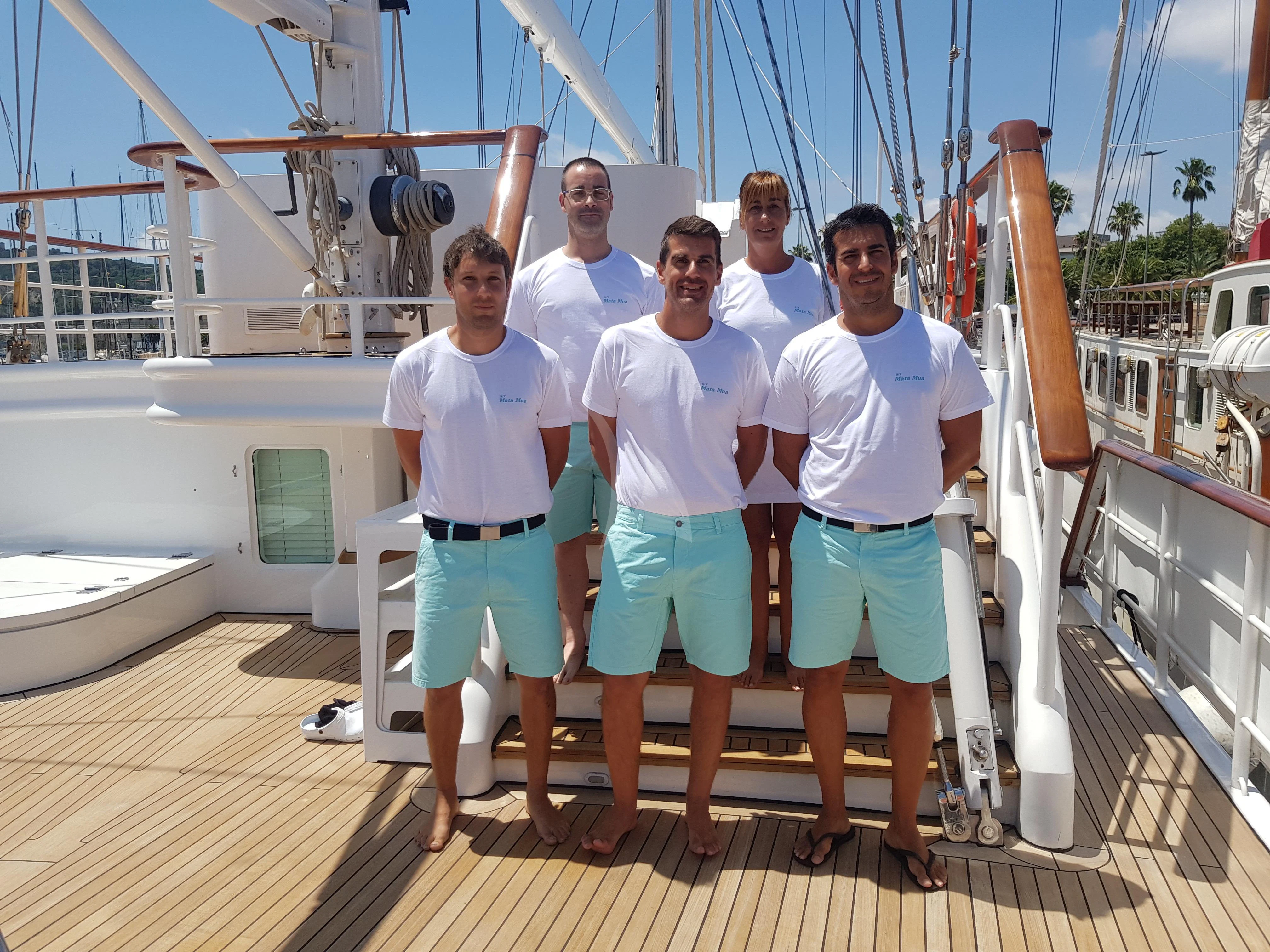 a group of men posing for a photo on a boat aboard MATA MUA Yacht for Sale