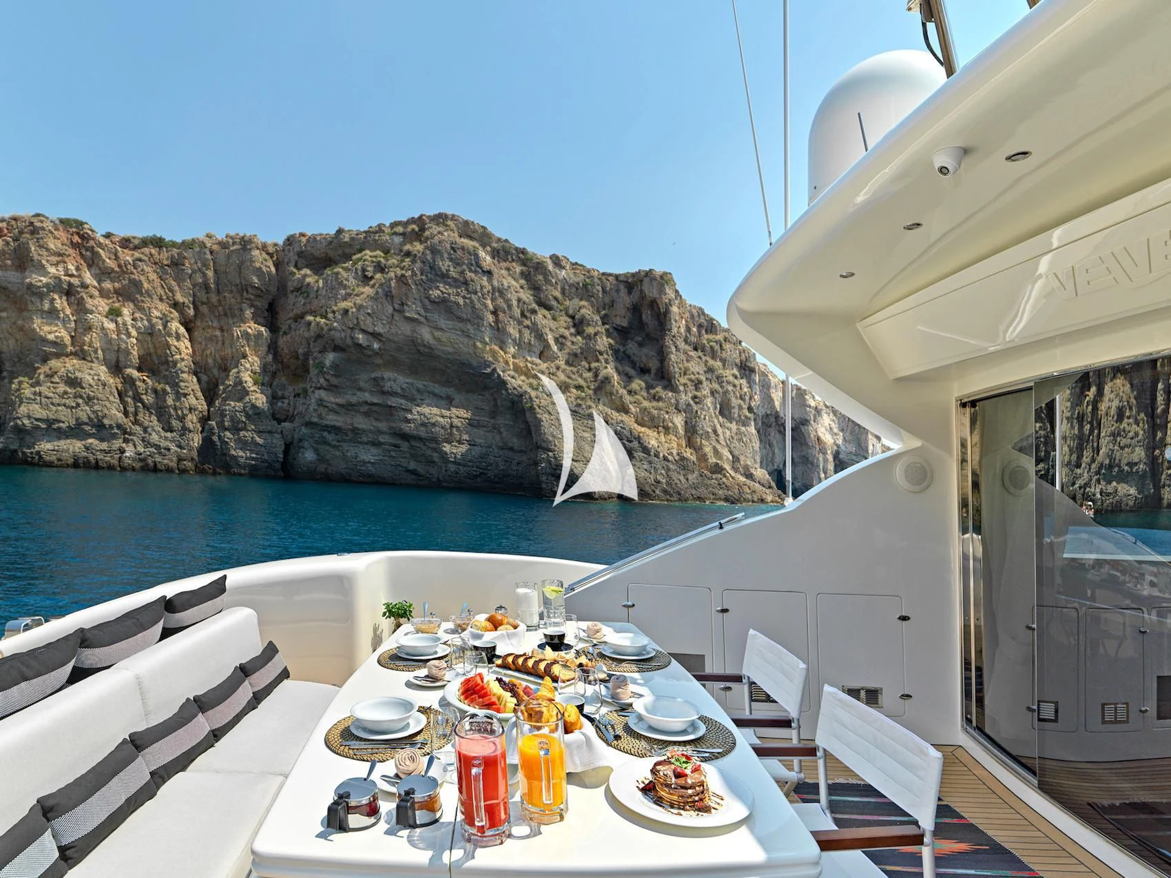 a table with plates and food on it next to a pool of water aboard RUBY Yacht for Charter