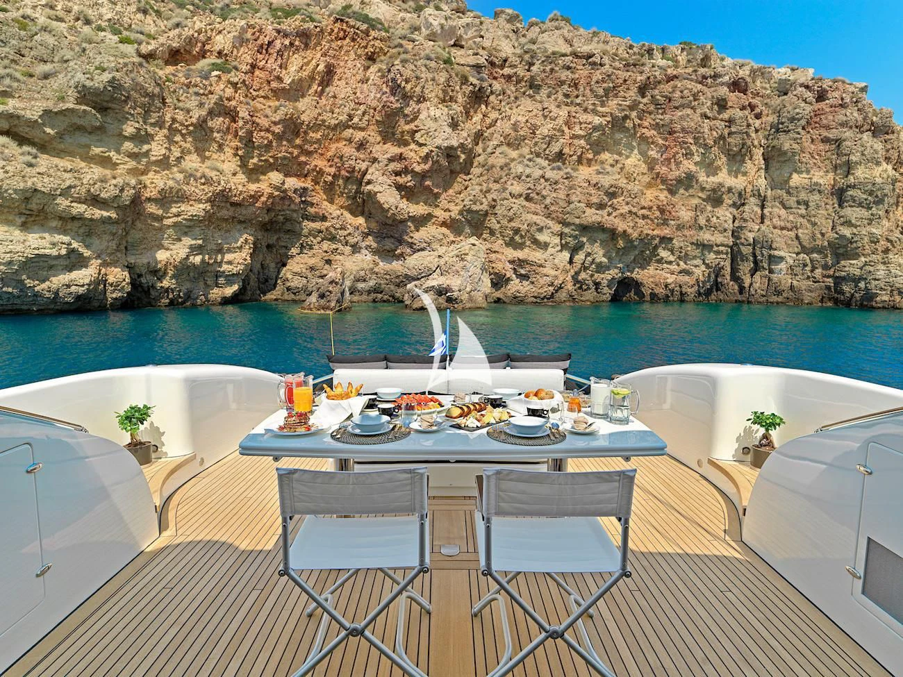 a table set for a meal on a balcony overlooking a body of water aboard RUBY Yacht for Charter