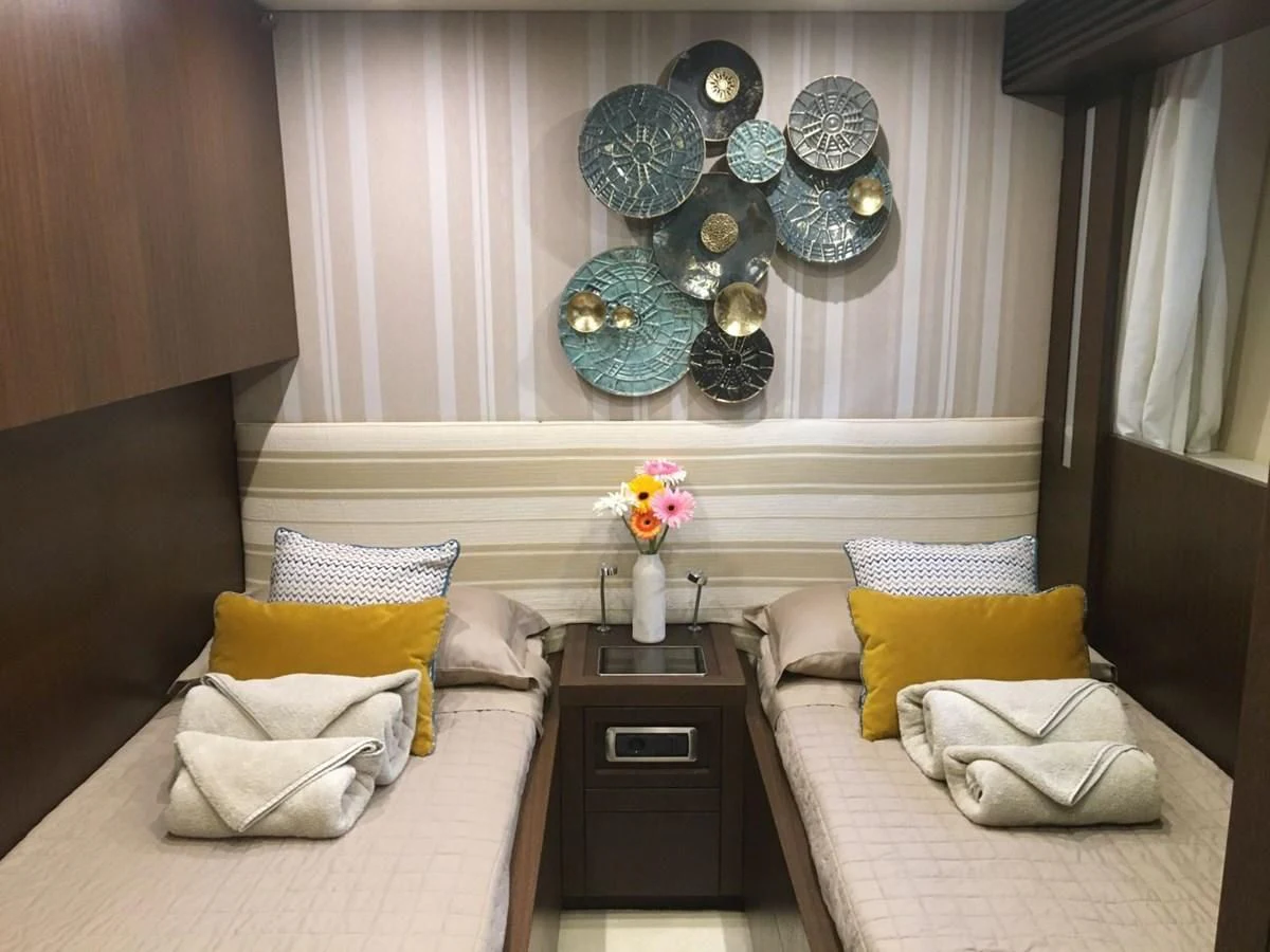 a room with a bed and a table with a flower vase on it aboard RUBY Yacht for Charter