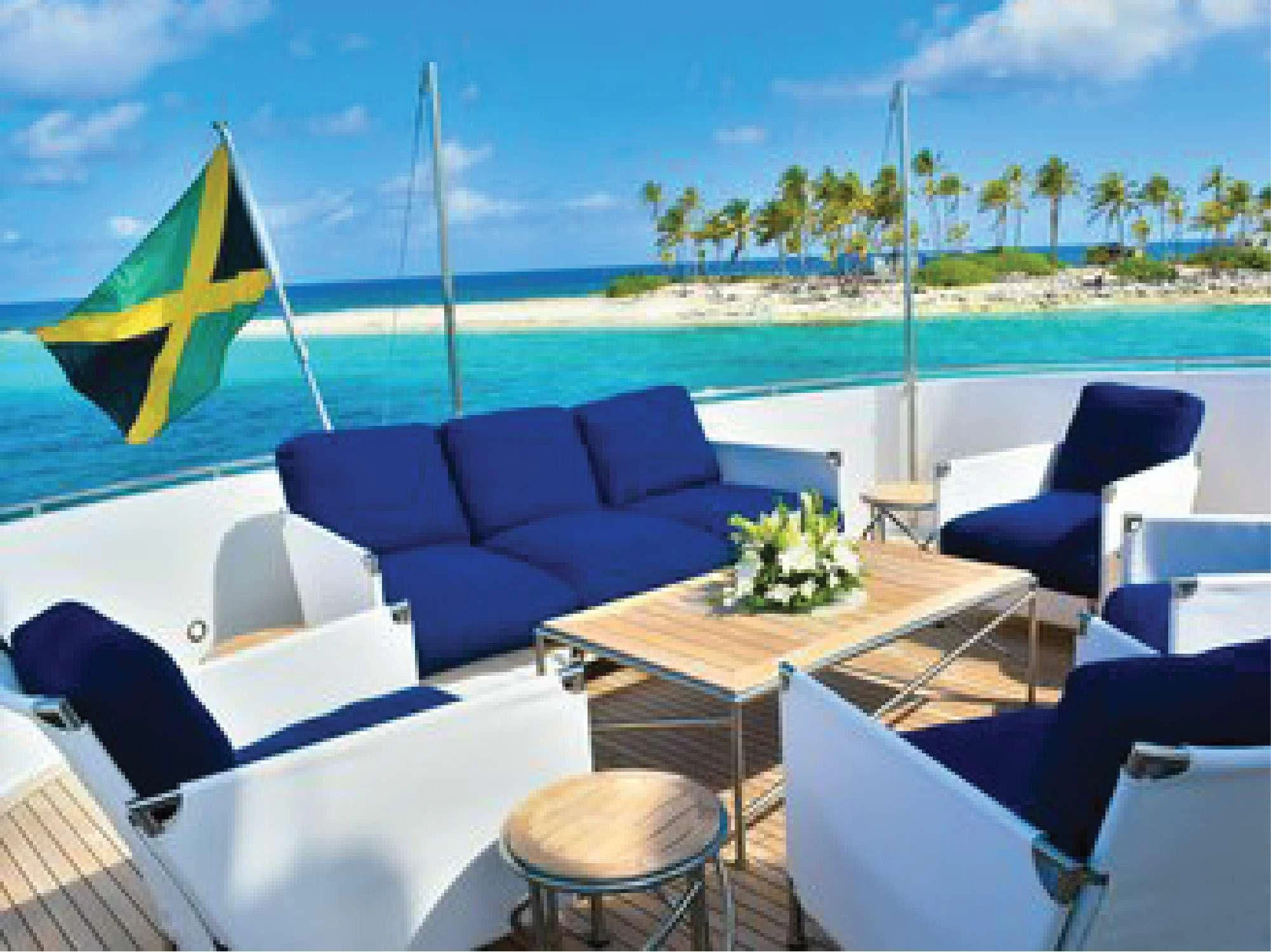 a table and chairs on a deck overlooking a beach aboard OCTOPUSSY Yacht for Sale