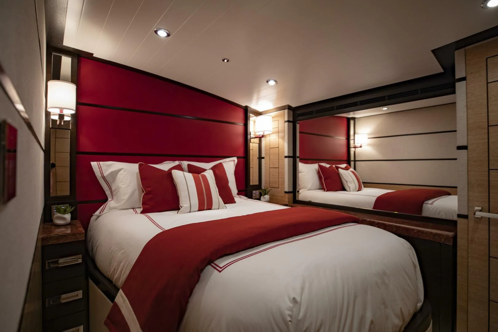 a bed with red pillows aboard III AMIGOS Yacht for Sale