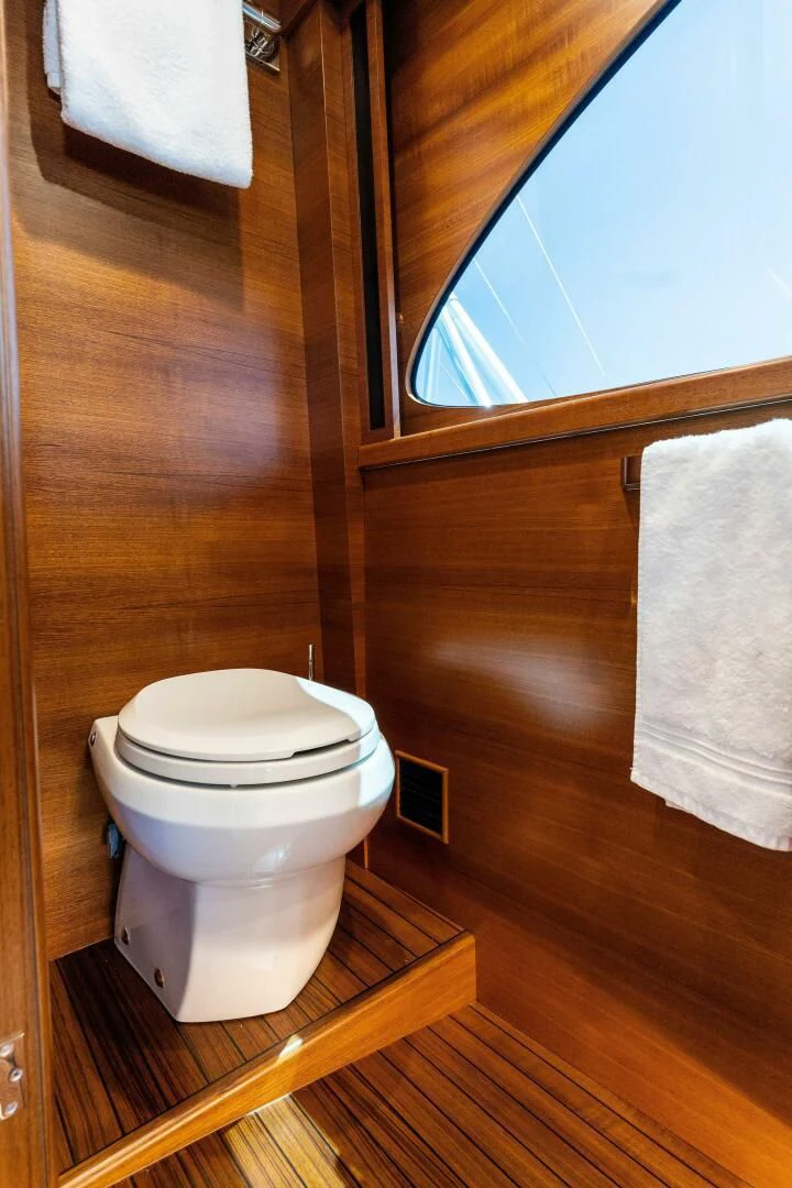 a bathroom with a toilet and a towel on the wall aboard III AMIGOS Yacht for Sale