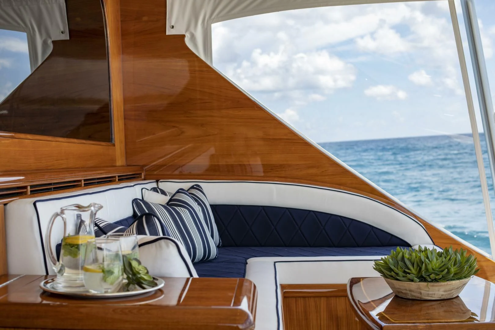 a table with a glass and a view of the ocean aboard III AMIGOS Yacht for Sale