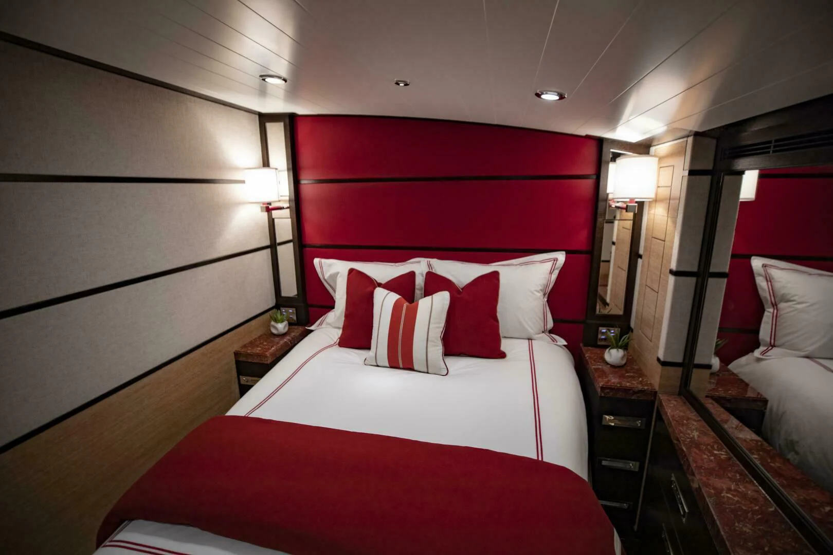 a bed with red pillows aboard III AMIGOS Yacht for Sale