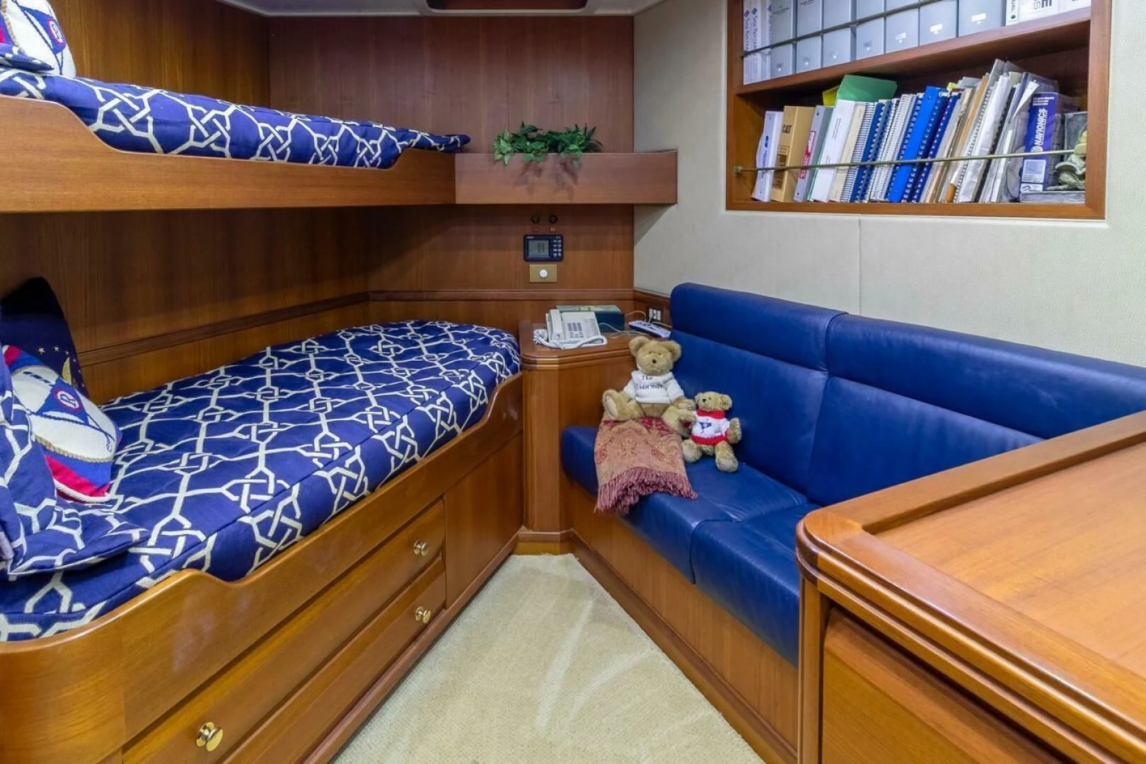 a room with a blue couch and a blue couch and a shelf with books aboard CHAIRMAN Yacht for Sale