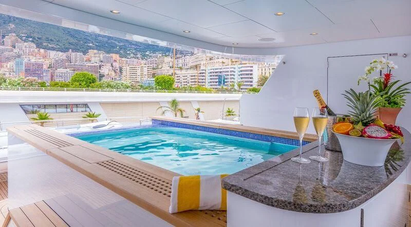 a pool with a glass of wine and a city in the background aboard LADY BETH Yacht for Sale