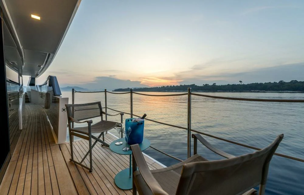 a deck with a chair and a body of water and a sunset aboard DILARA Yacht for Sale