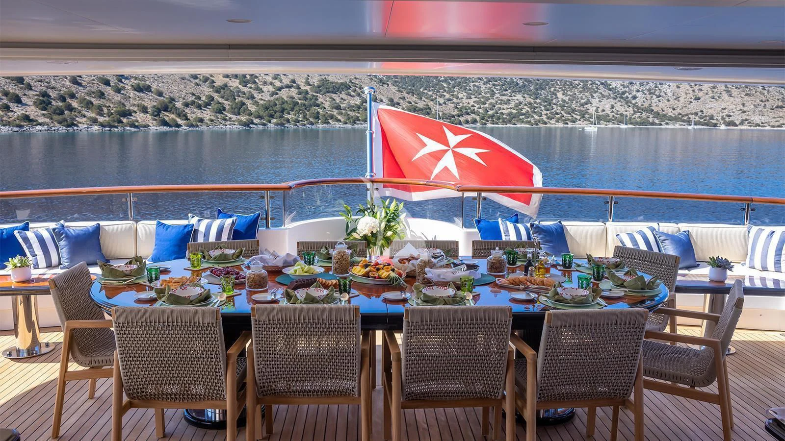 a table set with chairs and umbrellas on a patio with a large body of water in the aboard DILARA Yacht for Sale