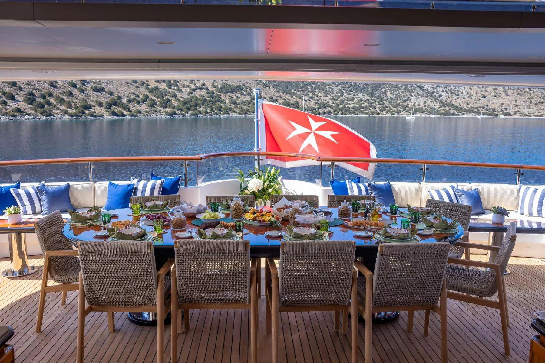 a table set up with chairs and umbrellas on a patio aboard DILARA Yacht for Sale
