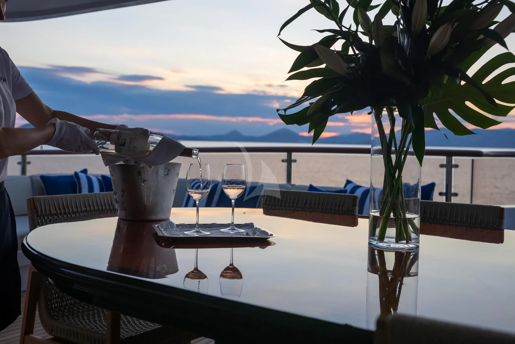 a table with wine glasses and a tree on the beach aboard DILARA Yacht for Sale