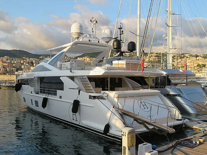 a boat docked at a pier with HMS M33 in the background aboard NEMESIS Yacht for Sale