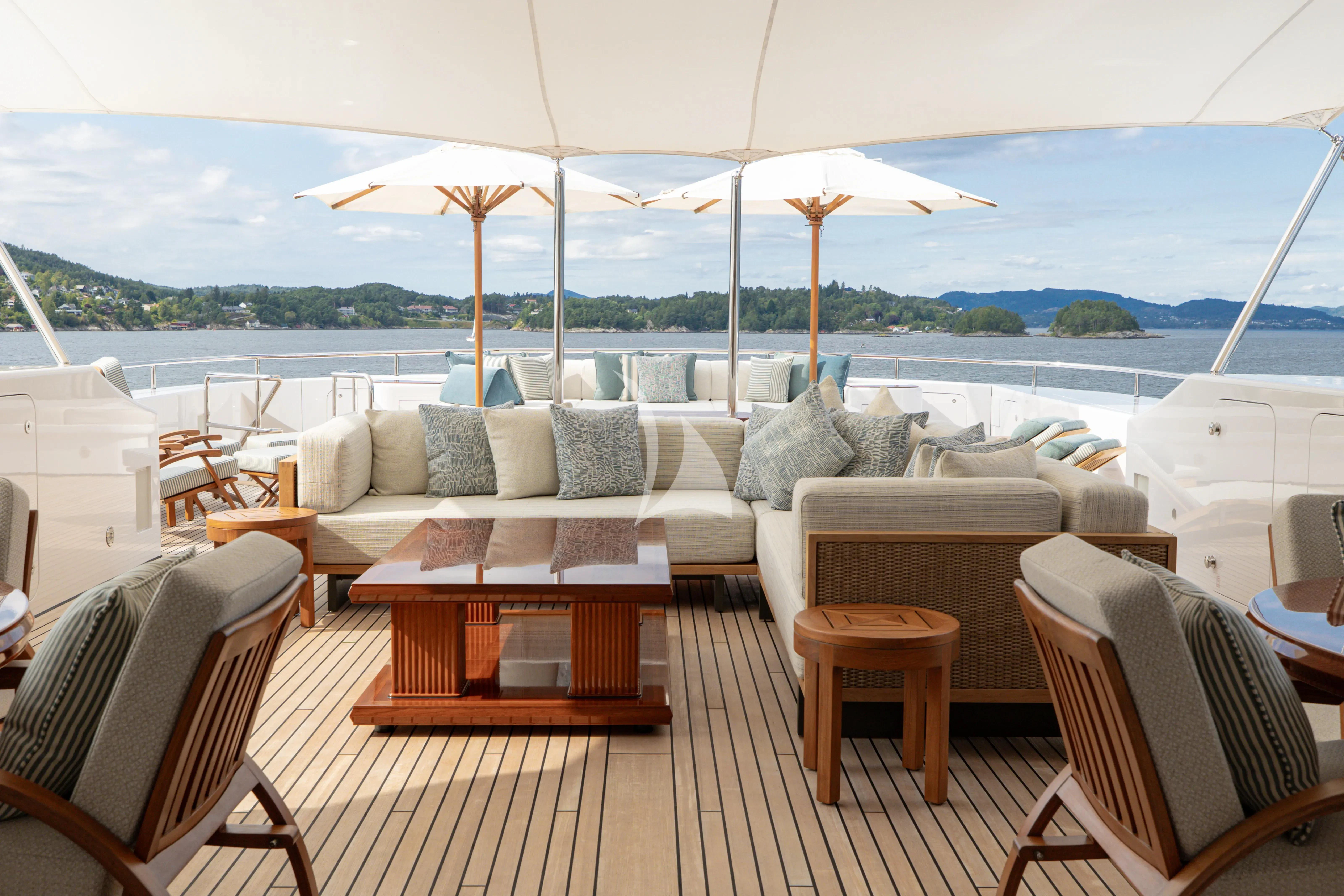 a large white sofa and chairs on a deck with a body of water in the background aboard NECTAR Yacht for Sale