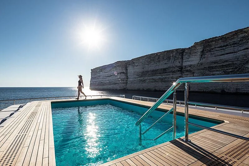 a person walking on a boardwalk next to a pool of water aboard MAR Yacht for Sale