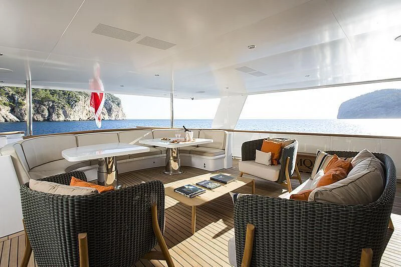 a room with a couch and a table with a plane in the background aboard EMERALD Yacht for Charter