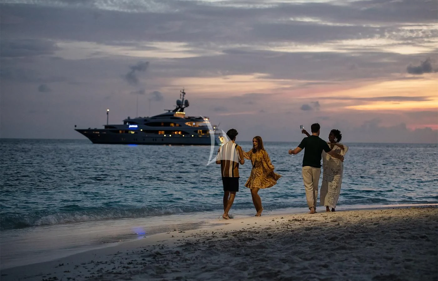 a group of people on a beach looking at a boat in the water aboard JAGUAR Yacht for Charter