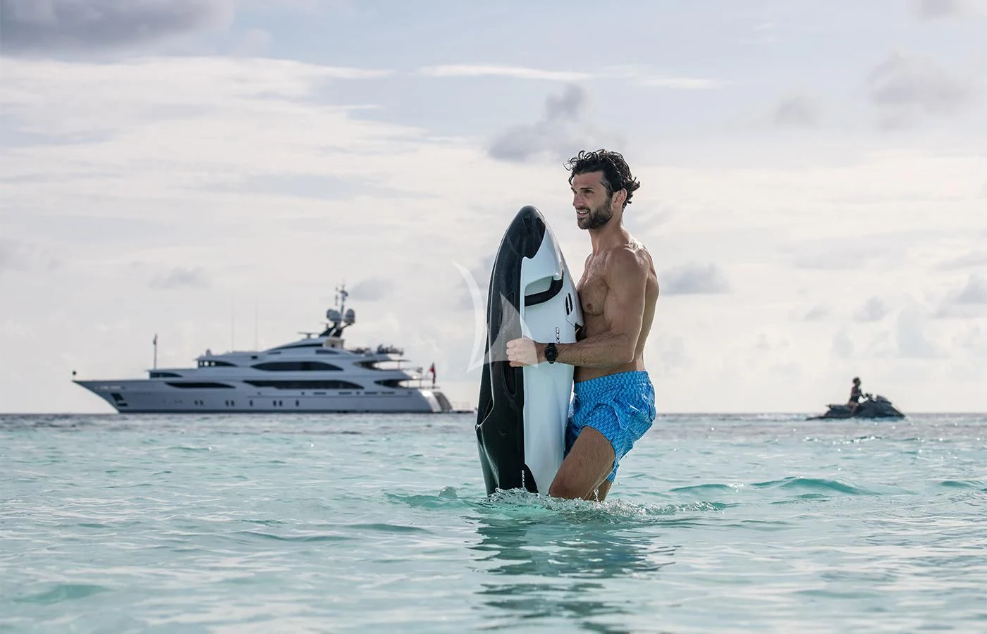 a man carrying a surfboard in the ocean aboard JAGUAR Yacht for Charter