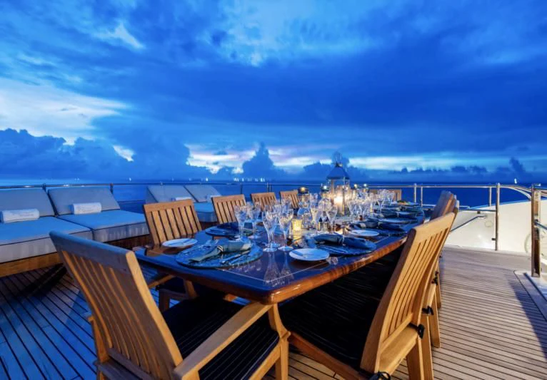 a table set for dinner on a deck overlooking a large body of water aboard JAGUAR Yacht for Charter