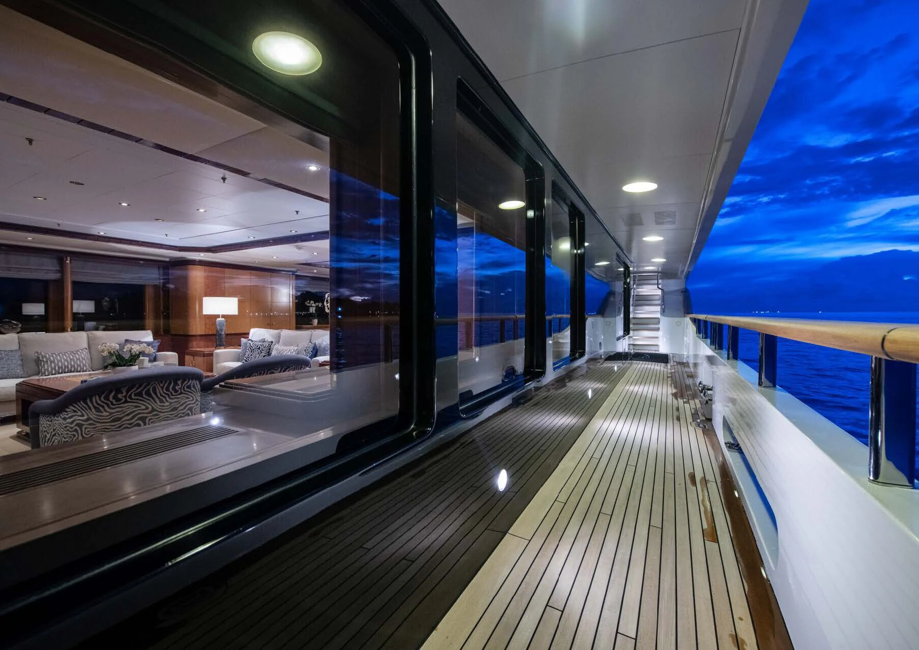 a long hallway with a row of beds and a large window aboard JAGUAR Yacht for Charter
