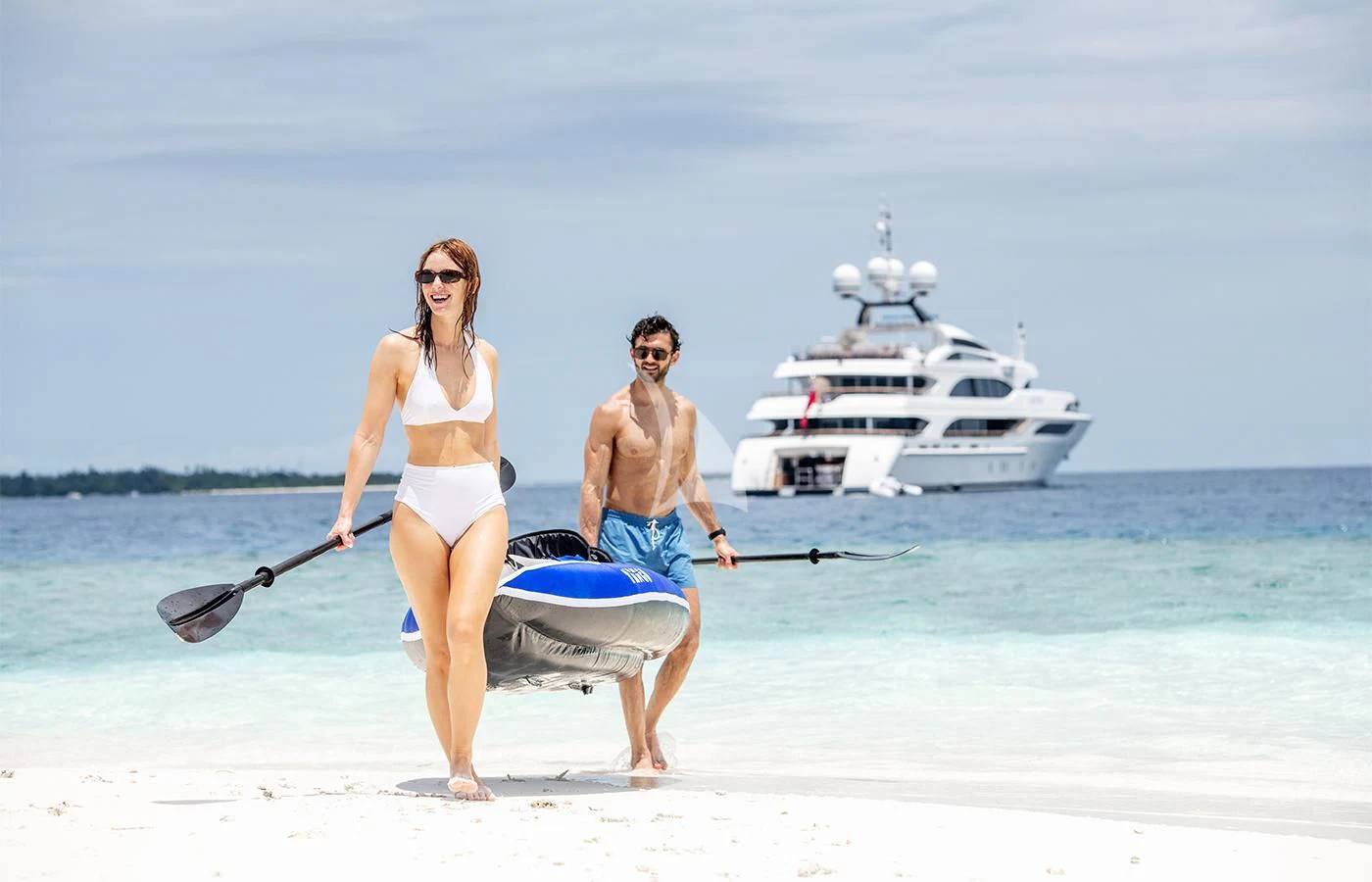 a man and woman holding a paddle and a boat on a beach aboard JAGUAR Yacht for Charter