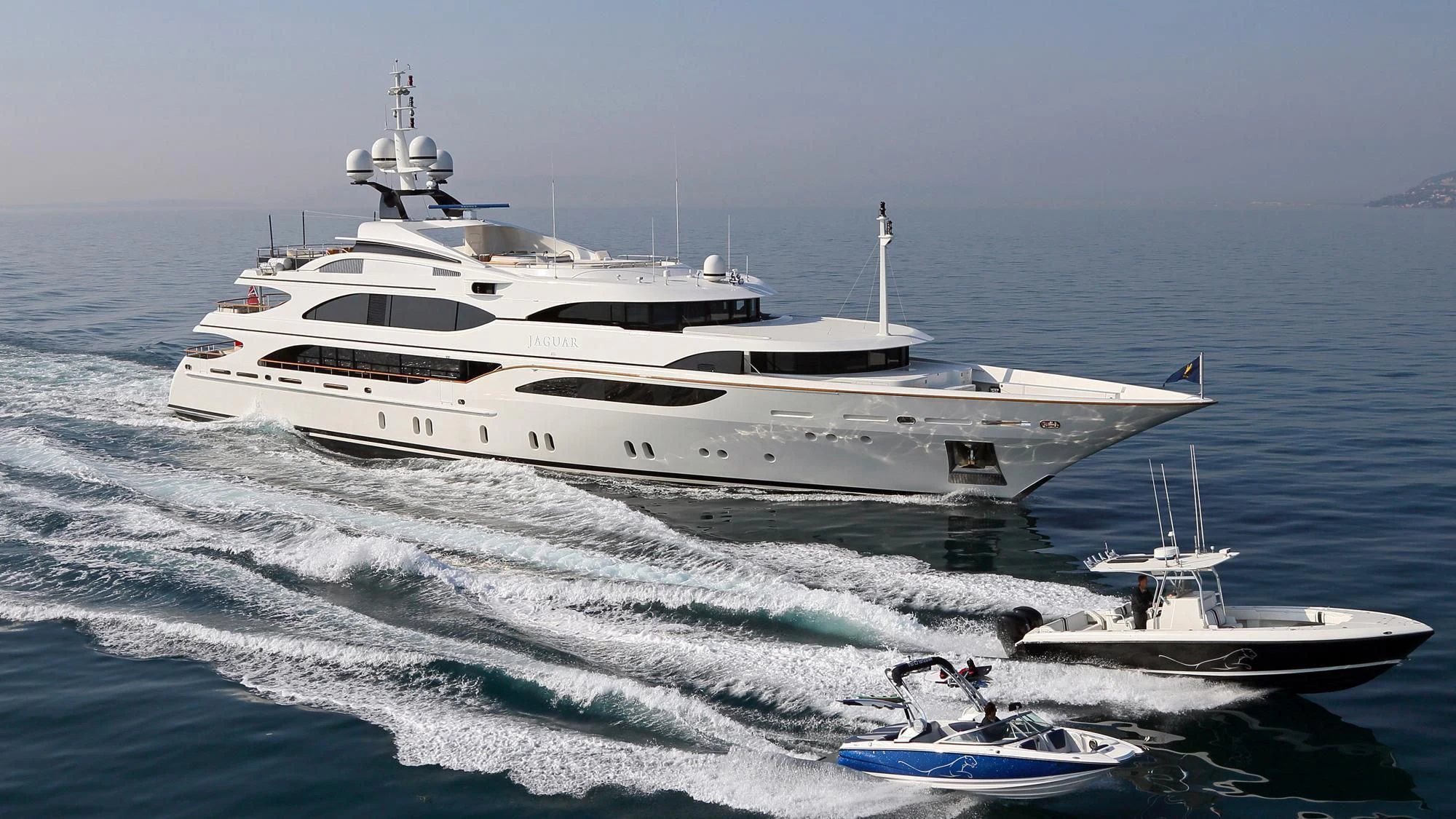 a white yacht with a smaller boat on the water aboard JAGUAR Yacht for Charter