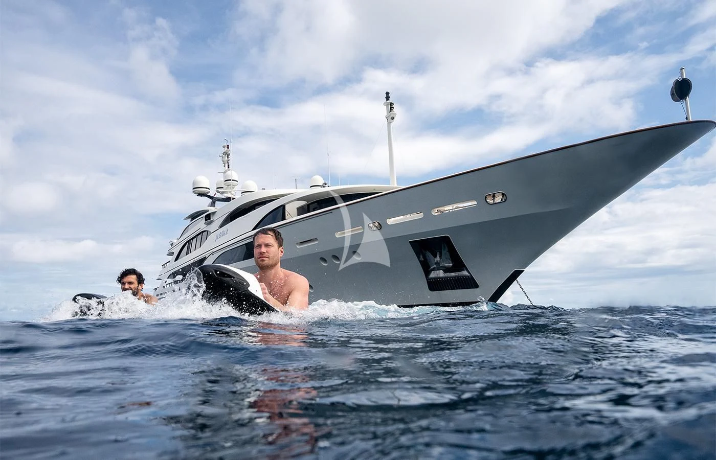 a man swimming in the ocean next to a boat aboard JAGUAR Yacht for Charter