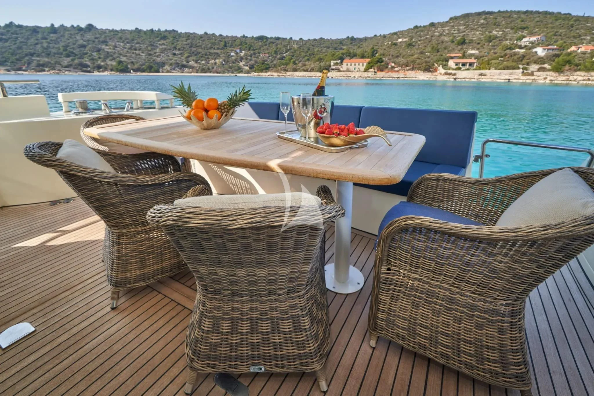 a table and chairs on a patio with a view of the water and mountains in the background aboard W Yacht for Sale