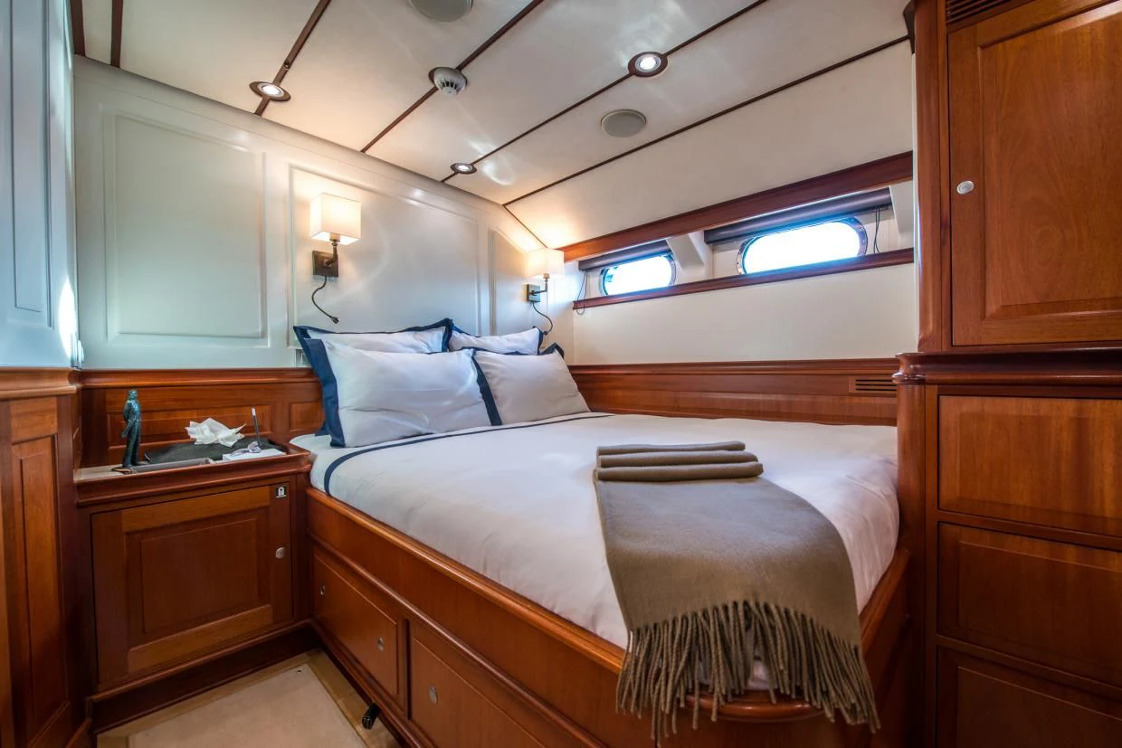 a bedroom with a bed and a dresser aboard AVENTURA Yacht for Sale