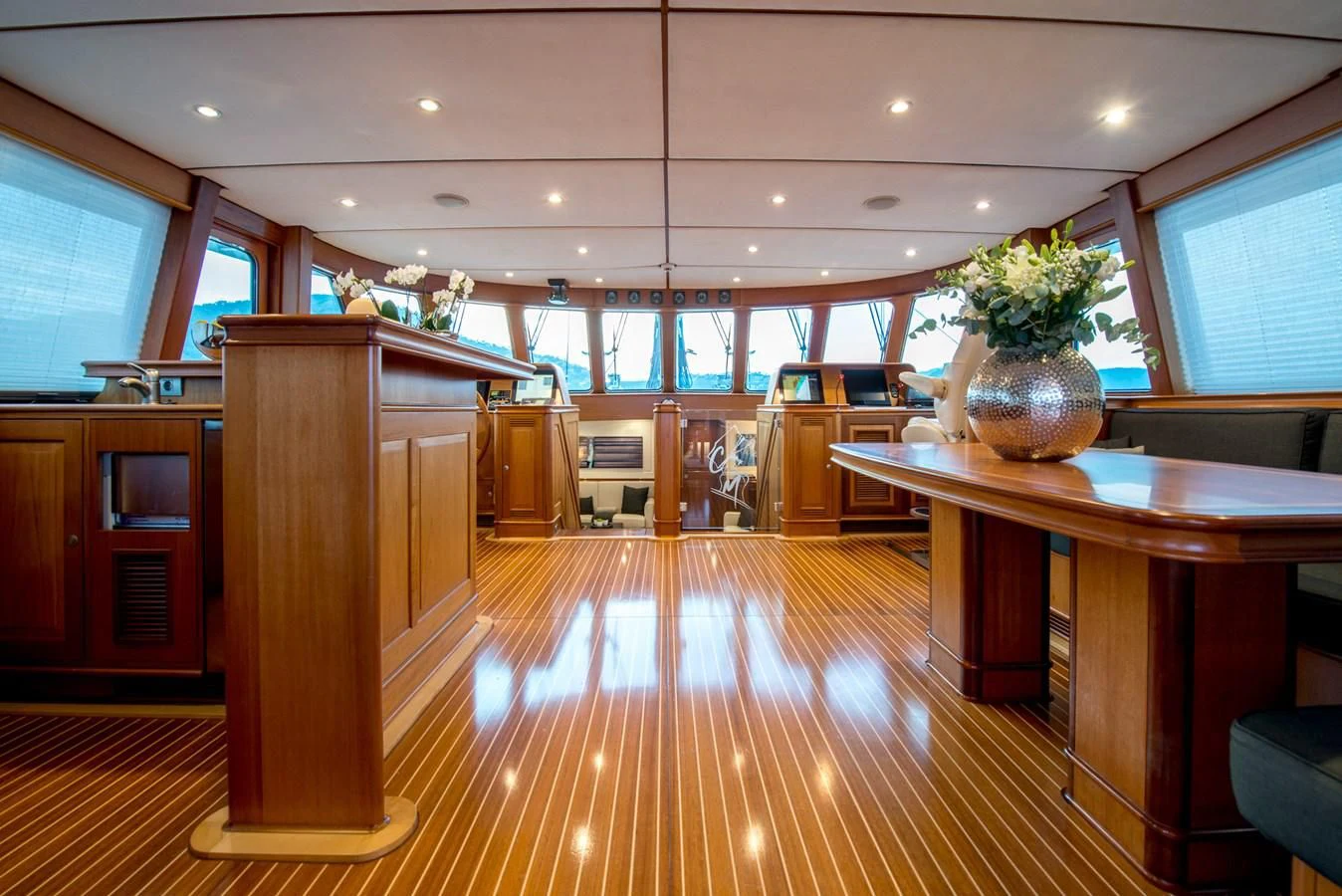 a large room with a wood floor and a large wood table with a plant in it aboard AVENTURA Yacht for Sale
