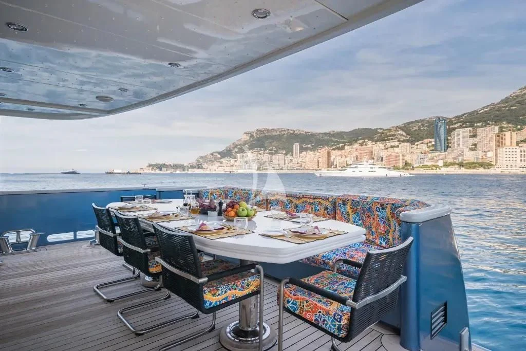 a table with chairs on it next to a body of water aboard IRAMA Yacht for Sale