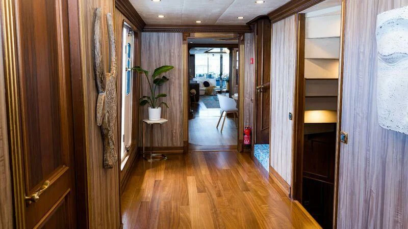 a hallway with a wood floor and a door with a plant on it aboard IRAMA Yacht for Sale