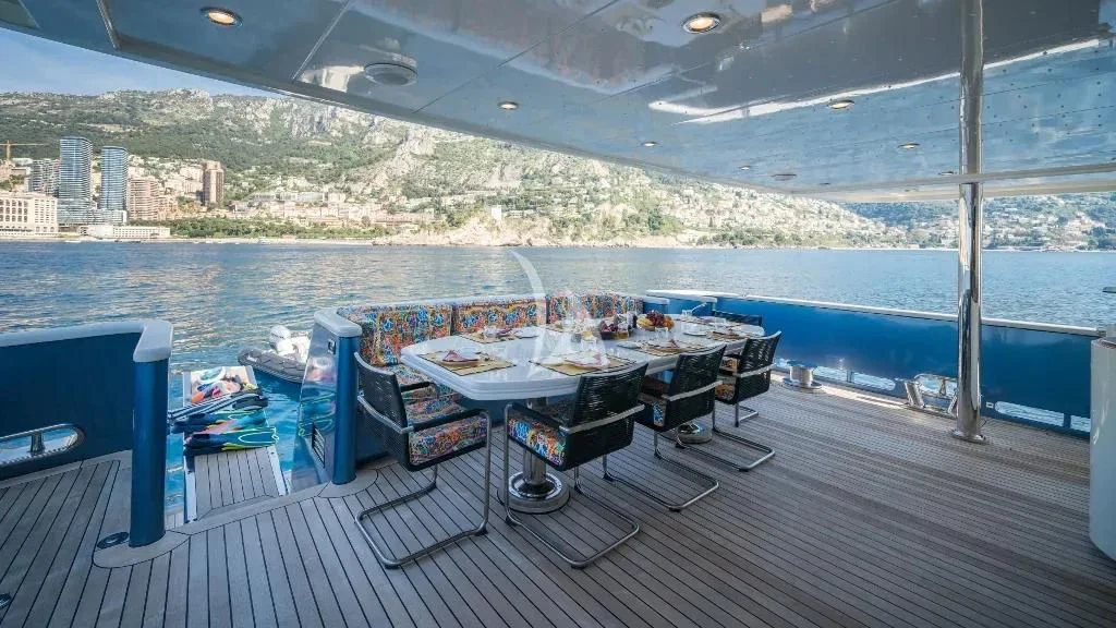 a table and chairs on a deck overlooking a body of water aboard IRAMA Yacht for Sale