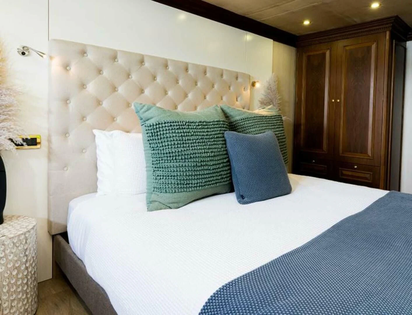 a bed with blue and white pillows aboard IRAMA Yacht for Sale