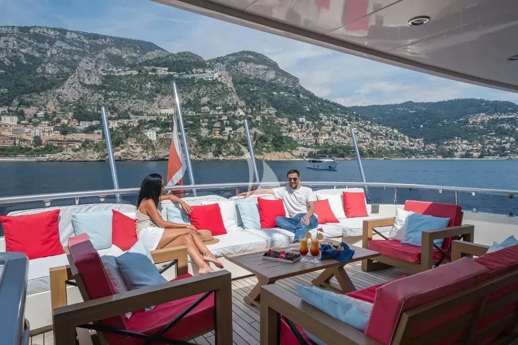 a couple sitting on a couch overlooking a large body of water aboard IRAMA Yacht for Sale