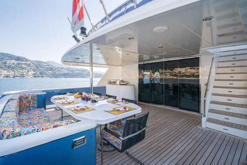 a deck with a table and chairs aboard IRAMA Yacht for Sale