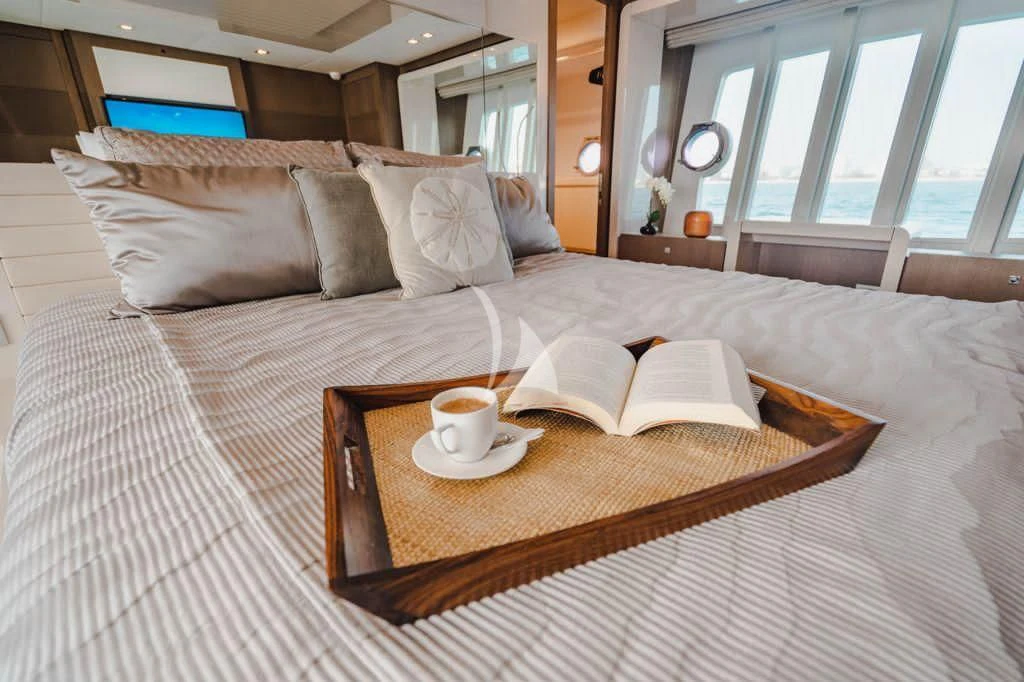 a bed with a tray of coffee and a book on it aboard TOP SHELF Yacht for Sale