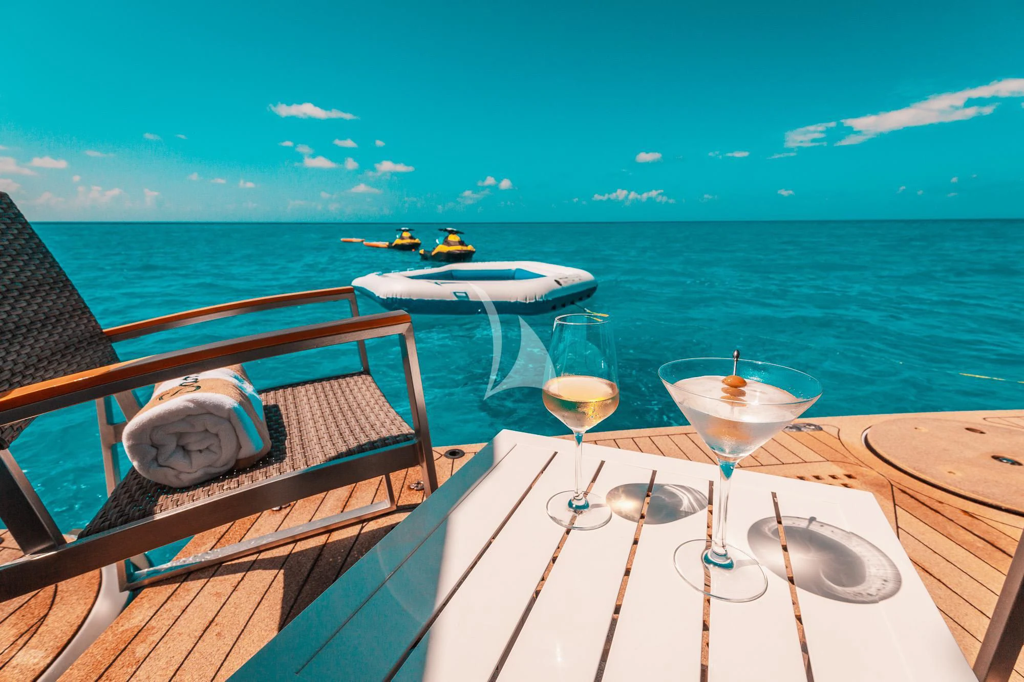 a table with glasses and a hat on it next to a body of water aboard SAMARA Yacht for Charter