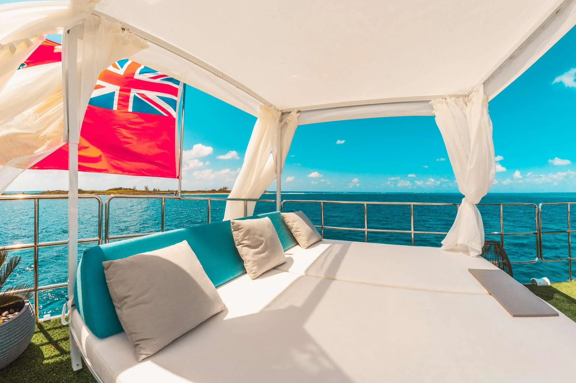 a bed with a white sheet and a blue ocean and a white tent aboard SAMARA Yacht for Charter