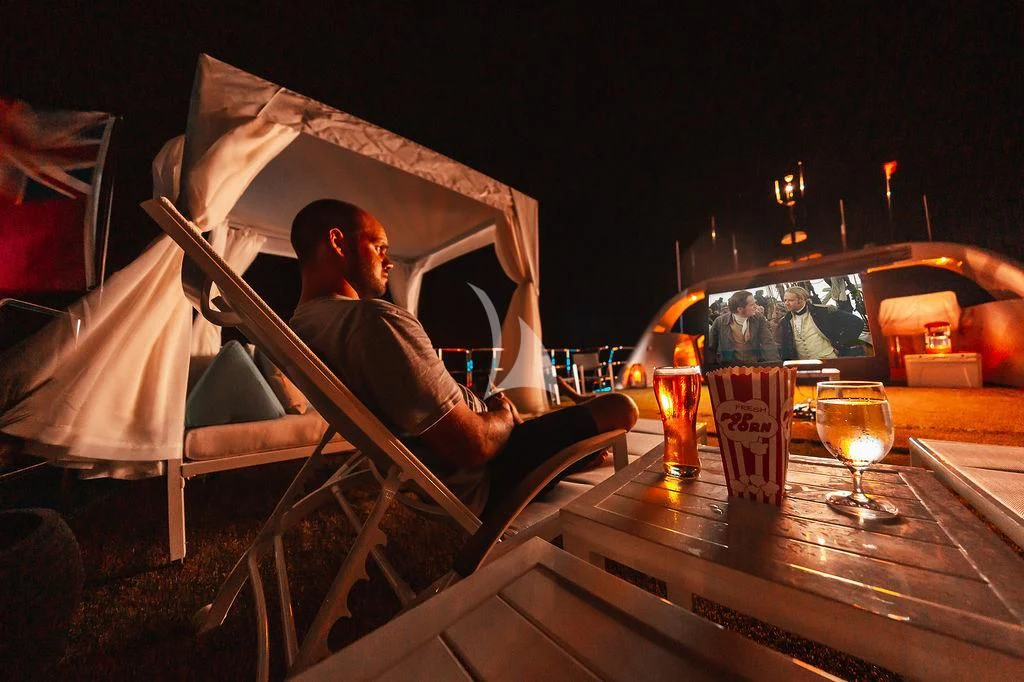 a person sitting in a chair in front of a fire aboard SAMARA Yacht for Charter