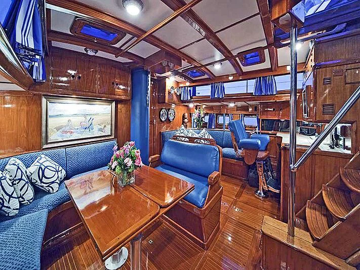 a room with a wood table and chairs and a large window aboard HERMIE LOUISE Yacht for Sale