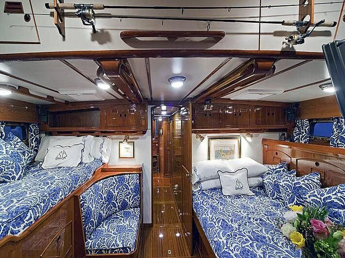 a room with wood walls and a bed with blue sheets aboard HERMIE LOUISE Yacht for Sale