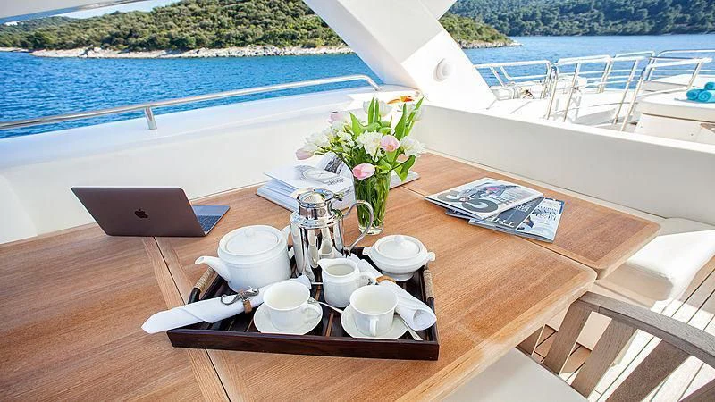 a table with cups and plates on it next to a pool aboard YVONNE Yacht for Sale