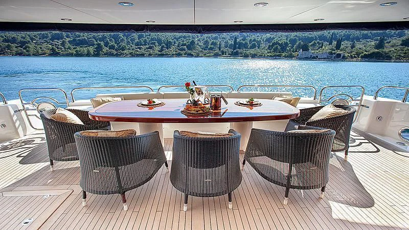 a table set for a meal on a deck overlooking a body of water aboard YVONNE Yacht for Sale